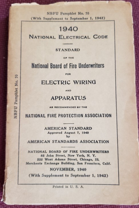 The worn cover of the 1940 edition 
 of the electrical code, a rectangle of maybe four by six inches, about a half-inch 
 thick
